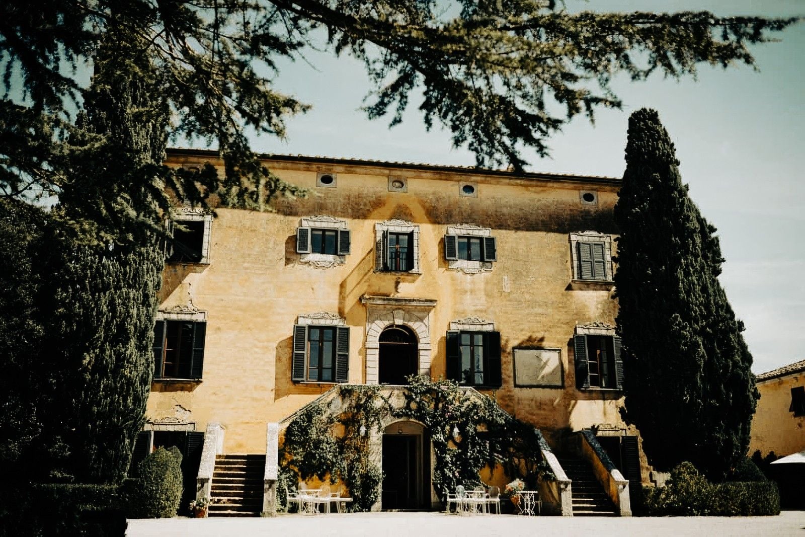 Historic villa surrounded by lush greenery and elegant landscaping, featuring arched entrance and ornate windows.