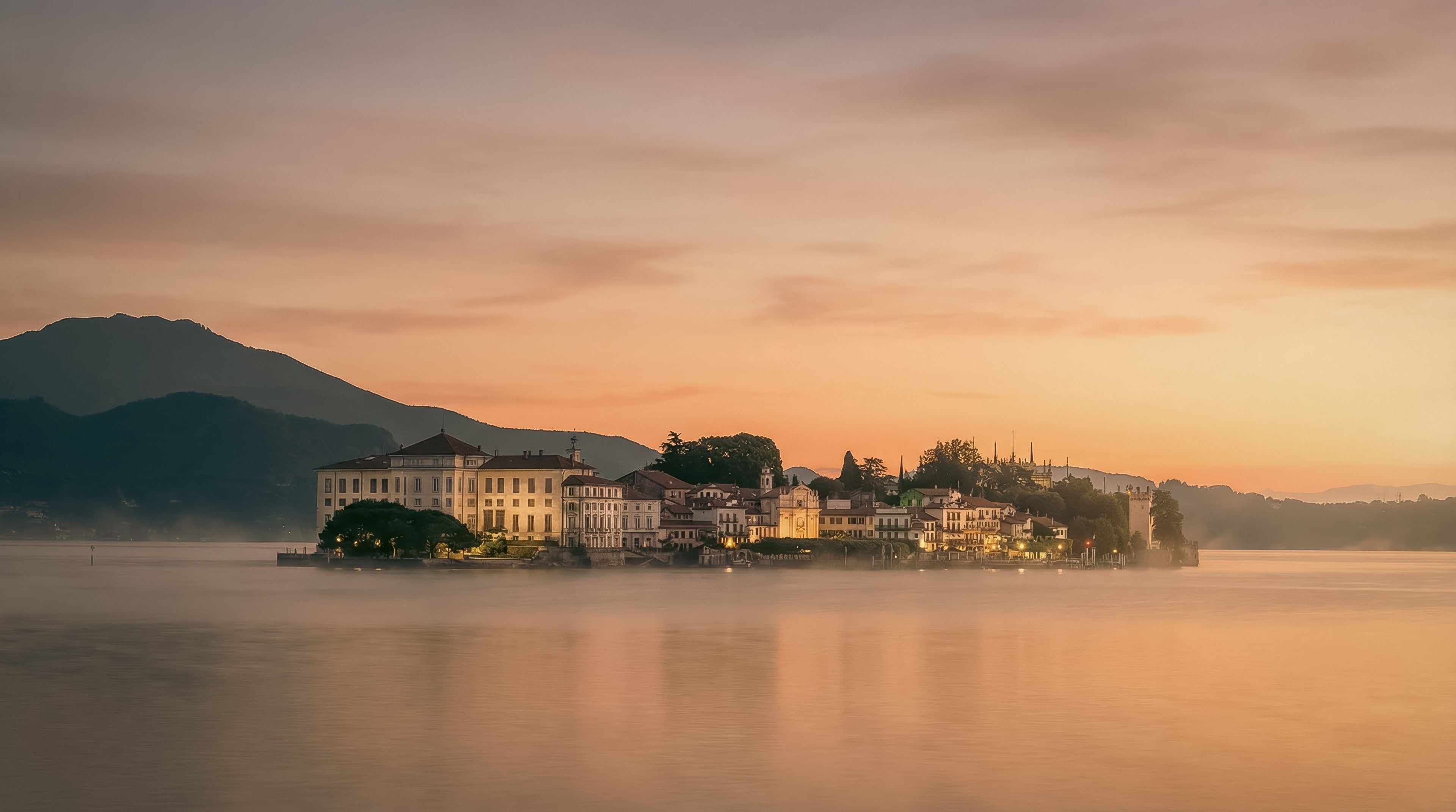 Isola Bella at sunset, with soft reflections on the water and a serene mountain backdrop.