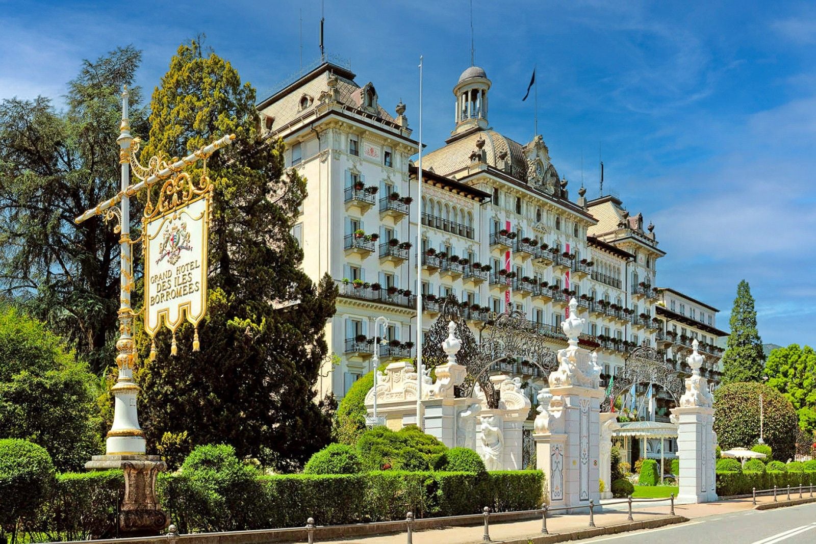 Grand Hotel des Bains, a historic luxury hotel with ornate architecture and lush gardens, set against a clear blue sky.
