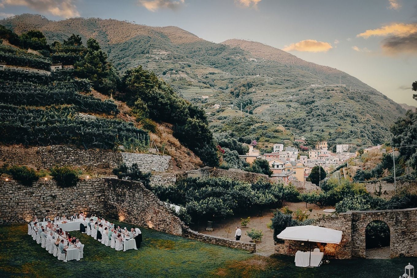 Outdoor wedding reception set against a scenic mountain backdrop, with long tables and lush greenery.