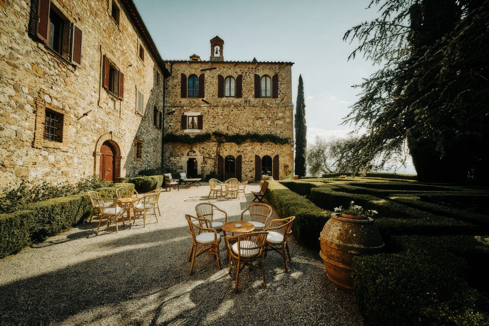 Charming stone villa with a manicured garden and outdoor seating under a clear sky, perfect for relaxation.