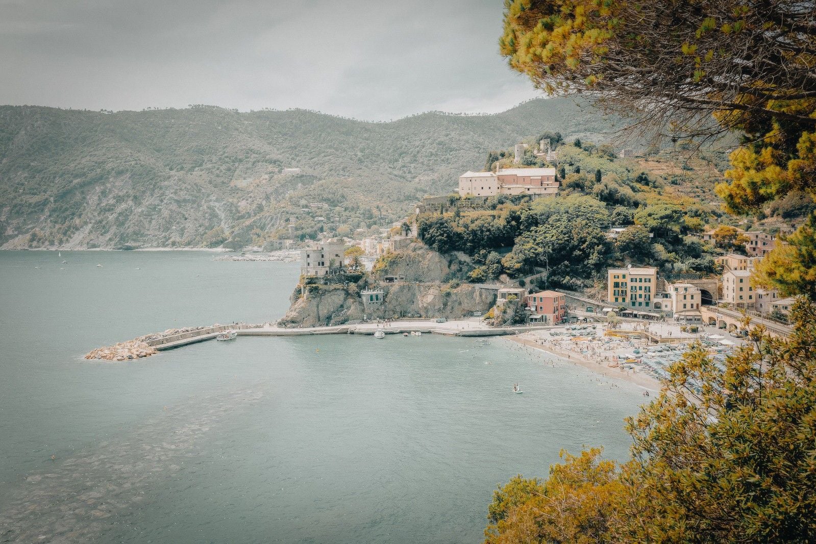 Coastal view of a picturesque village with colorful buildings nestled among green hills by the sea.