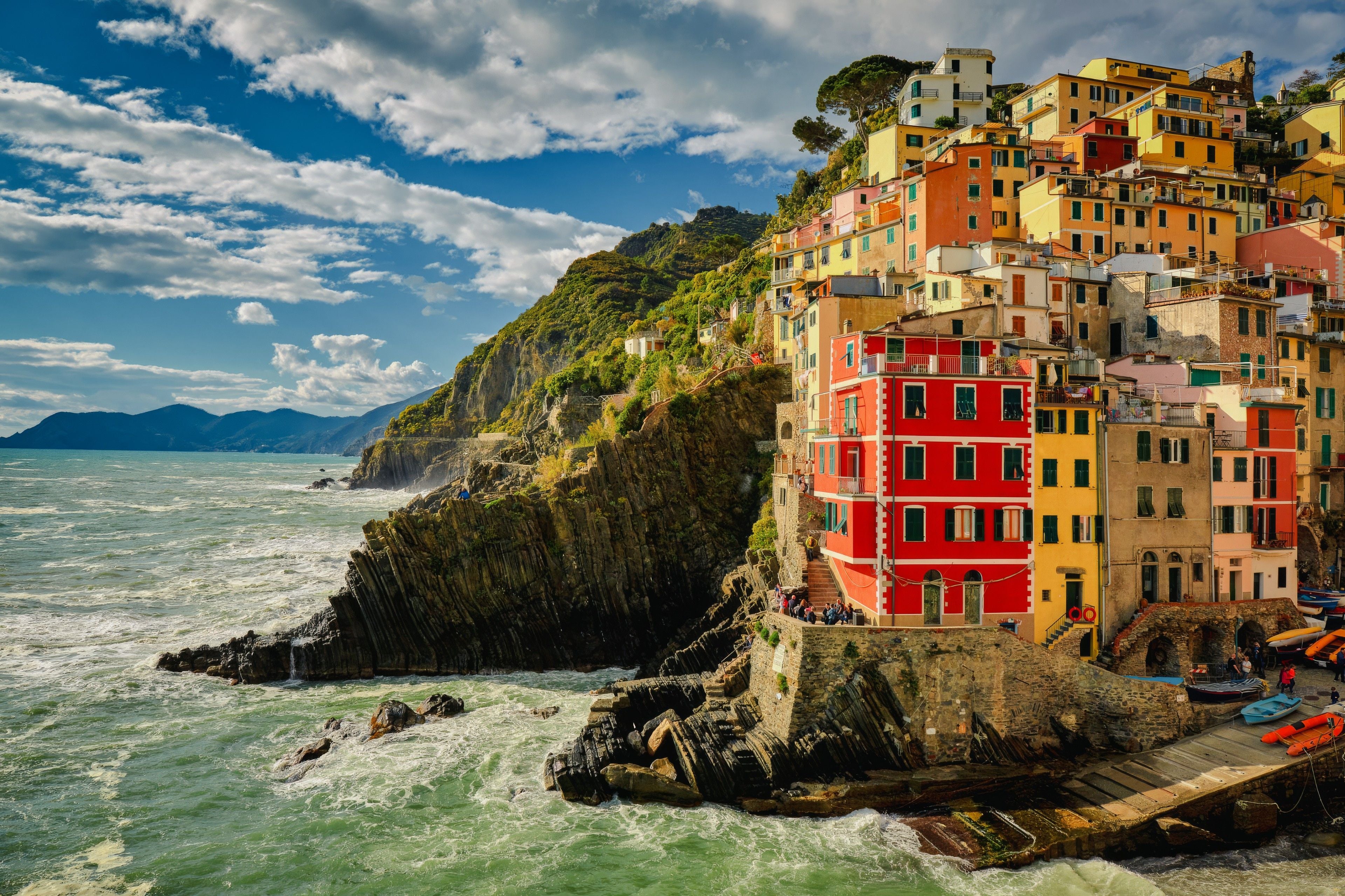 Colorful houses cling to rugged cliffs overlooking the vibrant sea in a picturesque coastal village.