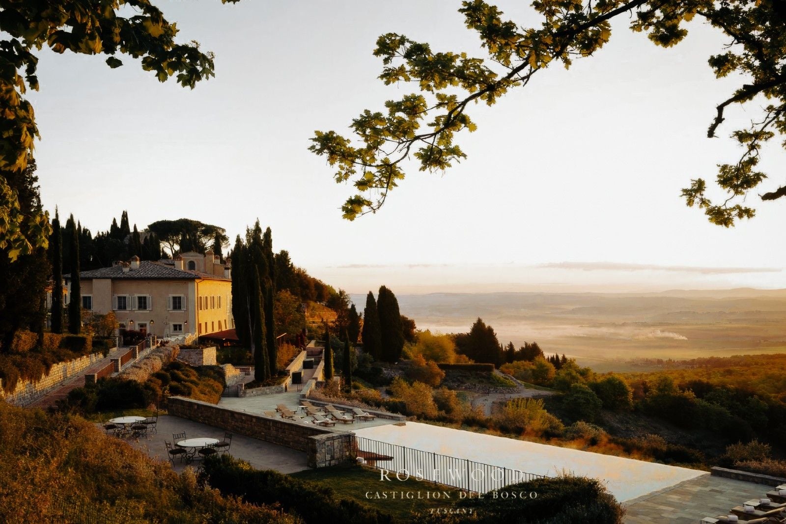 Sunrise over a Tuscan villa, overlooking lush hills and a tranquil landscape, with a swimming pool inviting relaxation.